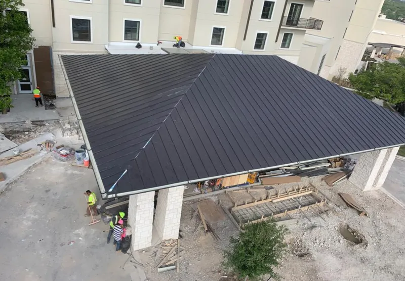 Metal roofing installation team working on a commercial building in West Loch Estate